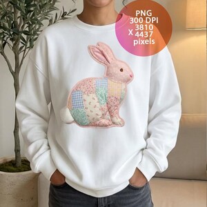 Puede incluir: Sudadera blanca con un diseño de conejo patchwork en patrones florales rosas, azules y amarillos. El conejo tiene orejas rosas y una cola blanca. La sudadera es de estilo casual y cómodo.