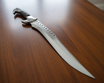 May include: A silver and black dagger with a curved blade and a decorative handle. The blade has a series of small holes along the spine. The dagger is lying on a wooden surface.