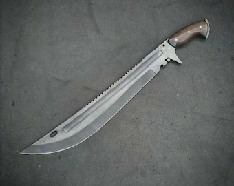 May include: A large machete with a curved steel blade featuring a serrated spine, a fuller groove, and a circular cutout near the tip. The handle is made of dark brown wood secured with two metal rivets, featuring a finger guard and a pommel.