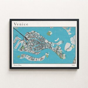 Può includere: Una planimetria di Venezia incorniciata, con una mappa dettagliata in blu, verde e bianco. La parola "Venice" è in alto, con "Street Plan" e "Italy" in basso. La cornice è nera.