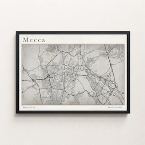 May include: A framed street plan of Mecca, Saudi Arabia. The map is in monochrome, with the city's road network clearly visible. The word "Mecca" is printed at the top, and "Street Plan" and "Saudi Arabia" are at the bottom.