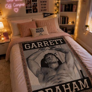 May include: A bedroom with a bed featuring a pink duvet and cushions. A throw blanket with the names "GARRETT GRAHAM" and a black and white image of a man is on the bed. A neon sign on the wall reads "just a girl who loves Off Campus".