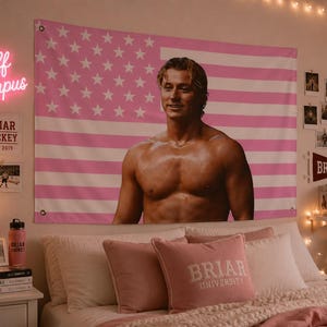 May include: A pink and white American flag tapestry with a shirtless man's image. The room features a bed with pink pillows, a neon "Off Campus" sign, and a "Briar Hockey" sign.