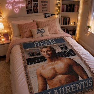 May include: A bedroom scene with a bed featuring a throw blanket with a male figure's image and the text "DEAN DI LAURENTIS". The room has a neon sign that says "just a girl who loves Off Campus". There are also decorative pillows and a bookshelf.