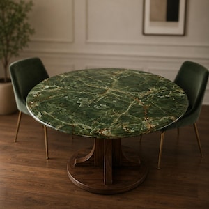 Puede incluir: Una mesa de comedor redonda con una tapa de mármol verde y una base de madera oscura. Dos sillas de terciopelo verde con patas doradas rodean la mesa. La tapa de la mesa tiene un patrón de vetas único.
