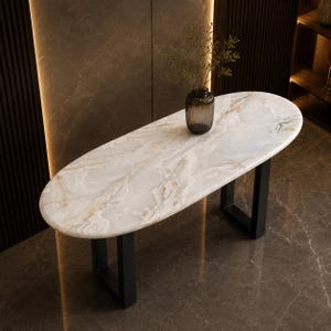 May include: An oval console table featuring a white and cream marble top with natural veining patterns, supported by two black metal U-shaped legs. A small, ribbed, dark glass vase containing a green plant sits on the center of the table surface.
