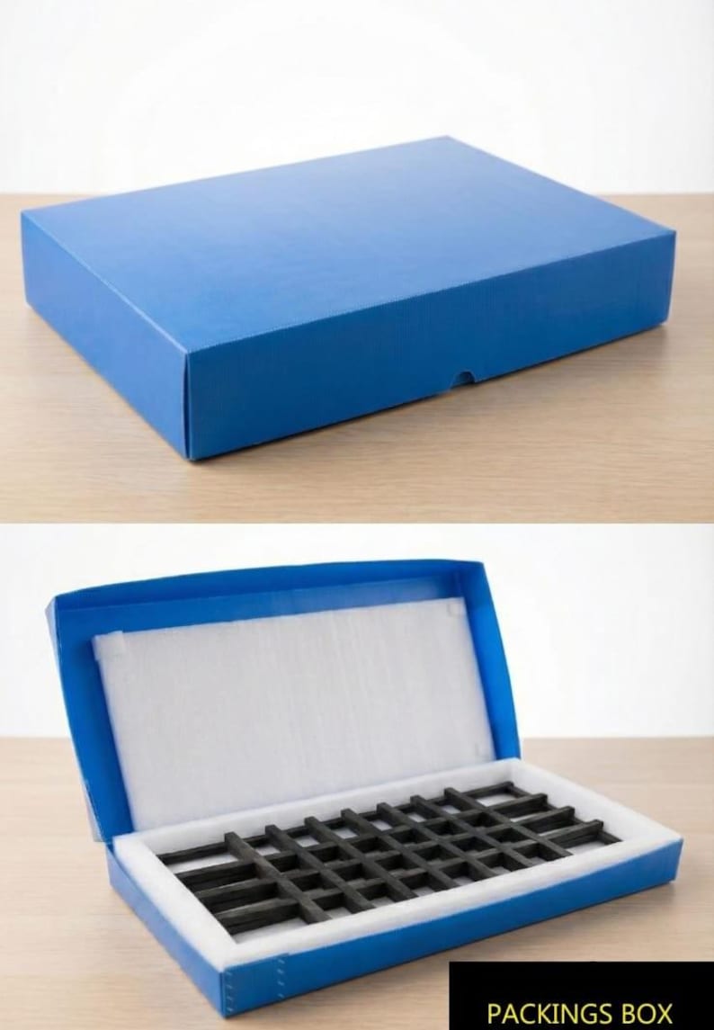 May include: A rectangular blue cardboard box shown closed and open. The interior features a white foam lining and a black grid-like insert for organisation. The text PACKINGS BOX is printed in white on a black background at the bottom right corner.