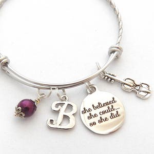 Peut inclure: Bracelet extensible en argent avec une perle violette, un charme avec la lettre "B" et un charme avec le texte "She believed she could... so she did".