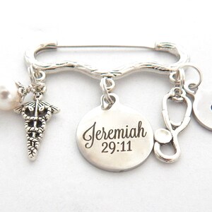 May include: Silver medical charm bracelet with a pearl, a caduceus, a stethoscope, and a round charm with the text "Jeremiah 29:11".