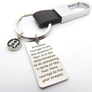 May include: Silver keyring with a black leather strap and a charm featuring the letter H. The keyring has a tag with the quote "Grandson, Courage is not the absence of fear, it is the determination to do something in spite of the fear. Have courage to live your dreams."