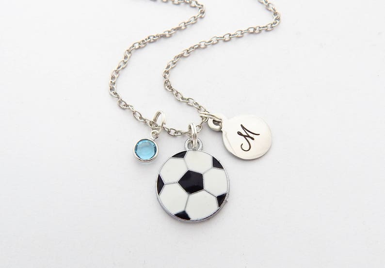 May include: Silver chain necklace with a soccer ball charm, a blue crystal charm, and a silver charm with the letter "M" engraved on it.