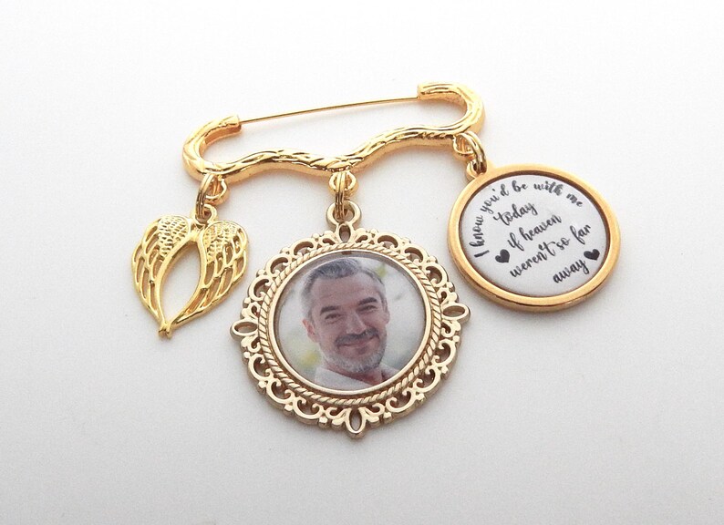 May include: Gold tone memorial brooch with a photo charm, a charm with angel wings, and a charm with the text "I knew you'd be with me today if heaven weren't so far away".