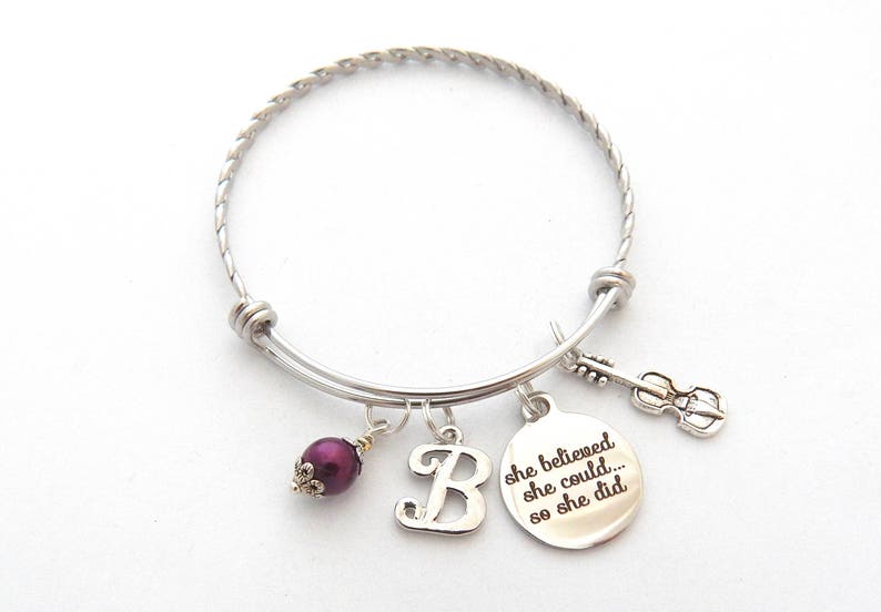 Peut inclure: Bracelet extensible en argent avec une perle violette, un charme avec la lettre "B" et un charme avec le texte "She believed she could... so she did".