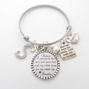 May include: Silver charm bracelet with a round charm that says "Sidnie, I promise to love you and your dad with my whole heart for my whole life Sharitha". The bracelet also has charms that say "Family", "Marriage made you family...Love made you my daughter", and a letter "S" charm.