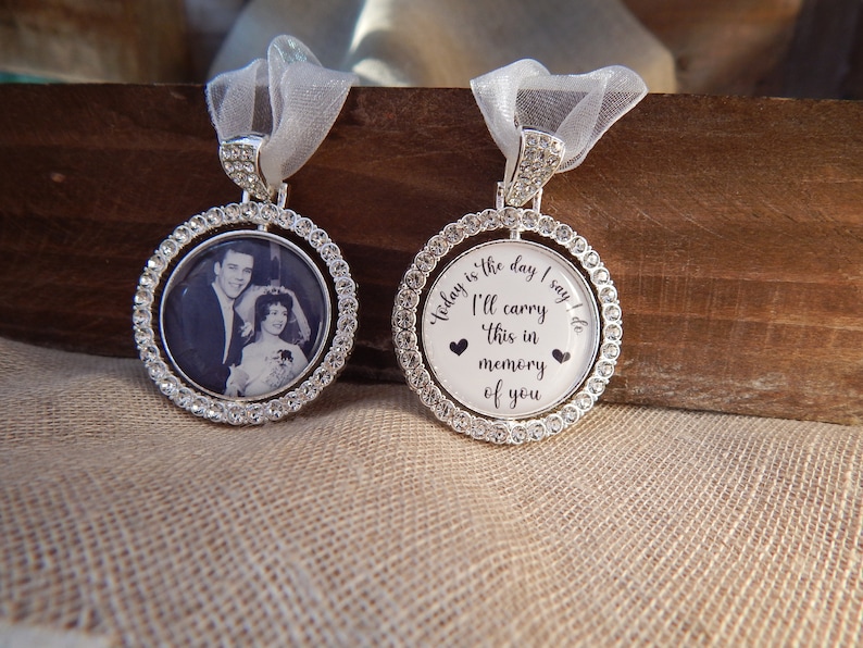 May include: Two circular silver-toned pendants framed with clear rhinestones. One pendant features a black and white photograph of a couple. The other pendant displays the text: Today is the day I say I do, I'll carry this in memory of you.