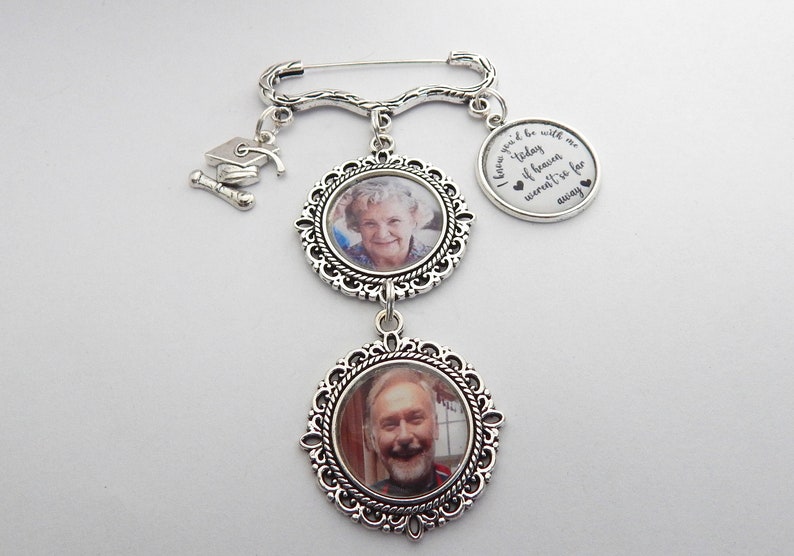 May include: Silver charm bracelet with two photo frames and a graduation cap charm. The charm has the text "I know you'd be with me today if heaven weren't so far away".