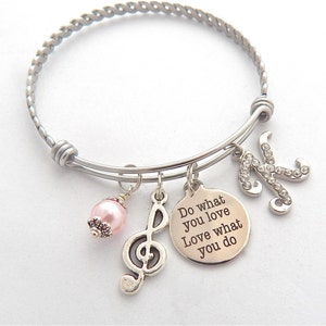 Peut inclure: Un bracelet argent&eacute; avec un charme qui dit "Do what you love Love what you do" et un charme avec une note de musique. Le bracelet a &eacute;galement un charme de perle rose et un charme avec la lettre K d&eacute;cor&eacute;e de strass.
