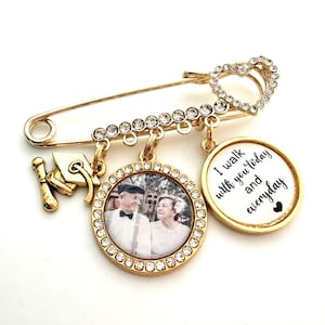 May include: Gold-toned memorial pin with a heart-shaped clasp and dangling charms. Charms include a miniature graduation cap, a photo pendant, and a round pendant with the text "I walk with you today and everyday."