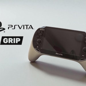 Könnte beinhalten: Eine PS Vita Handheld-Spielkonsole mit weißem Griffaufsatz. Die Konsole hat einen schwarzen Bildschirm und Tasten, mit dem Text "PSVITA" und "GRIP". Das Sony-Logo ist ebenfalls vorhanden.