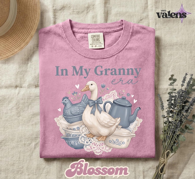 May include: A pink Comfort Colors t-shirt with the phrase "In My Granny Era" and a graphic of a goose, teapot, and bowls. The word "Blossom" is at the bottom. The shirt is size S-P-CH.