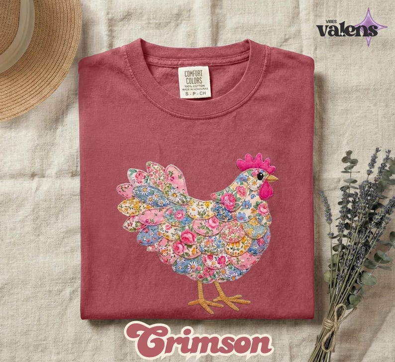 May include: Crimson-colored t-shirt with a floral chicken design. The chicken is made of fabric with pink, blue, and yellow floral patterns. The shirt has a crew neck and short sleeves. The brand name "Comfort Colors" is visible on the tag.