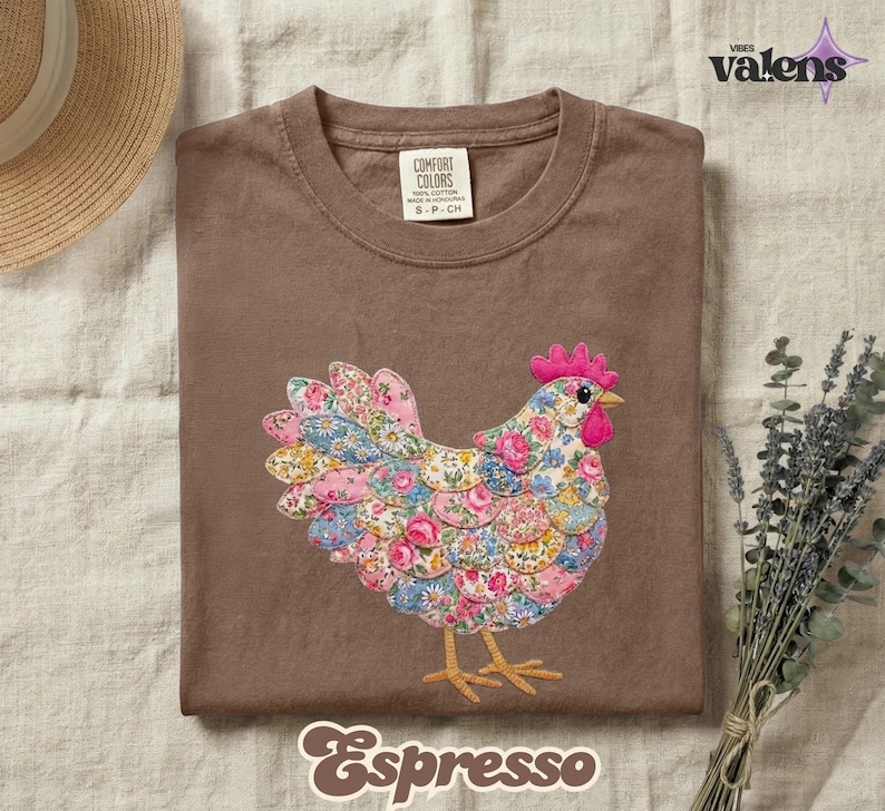 May include: Espresso-colored t-shirt featuring a colorful floral chicken design. The chicken has a pink comb and beak, with a body made of various floral patterns. The shirt is labeled "Comfort Colors" and "S-P-CH".