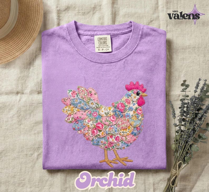 May include: A lilac-colored Comfort Colors t-shirt featuring a colorful floral chicken design. The chicken has a pink comb and beak, with a body made of various floral patterns. The word "Orchid" is written in a cursive font at the bottom.