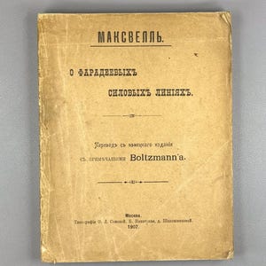 May include: A vintage book cover with text in a foreign language. The cover is a faded tan color with the title "МАКСВЕЛЛЬ" at the top. Below, the title continues with "О ФАРАДЕЕВЫХЪ силовыхъ ЛИНІЯХЪ." Additional text and a publisher's mark are also visible.