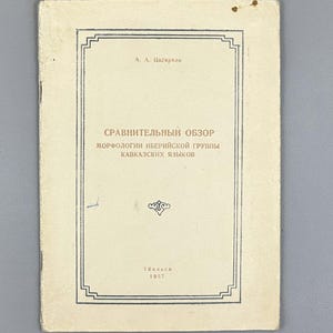May include: A vintage book cover with text in a foreign language. The cover is off-white with a black border and text. The title is in a large font, and the author's name is at the top. The year 1957 is at the bottom.