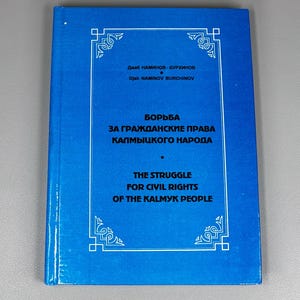 Peut inclure: Un livre bleu avec du texte blanc et des bordures décoratives. Le titre, en anglais et en russe, est « La lutte pour les droits civiques du peuple kalmouk ». Le nom de l'auteur est également affiché.