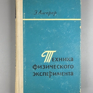 May include: A vintage book with a teal cover featuring the title in Russian. The book's title is "Technique of Physical Experiment". The author's name, "E. Angerer", is printed at the top. The spine is off-white.