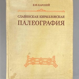 May include: A vintage book with a light tan cover. The title "СЛАВЯНСКАЯ КИРИЛЛОВСКАЯ ПАЛЕОГРАФИЯ" is printed in dark red Cyrillic script. The author's name, "Е.Ф. КАРСКИЙ", is at the top. An orange decorative design is at the bottom.
