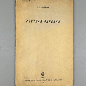 May include: A white ceramic mug with a black handle and the text "But First, Coffee" in a black, bold font. The mug is sitting on a white surface. The mug is approximately 4 inches tall.