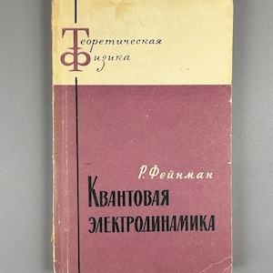 May include: A vintage book with a cream and burgundy cover. The top section of the cover is cream with the title in Russian. The bottom section is burgundy with the title "Kvantovaya Elektrodinamika" and the author's name.