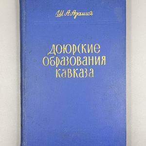 May include: A blue book with gold lettering. The title is in a foreign language, with the author's name at the top. The book's cover is a solid blue color.
