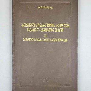 May include: A vintage book with a brown cover and gold lettering. The text on the cover is in a foreign language. The book appears to be a scholarly work, possibly a textbook or academic publication. The book's title and author are displayed prominently on the cover.