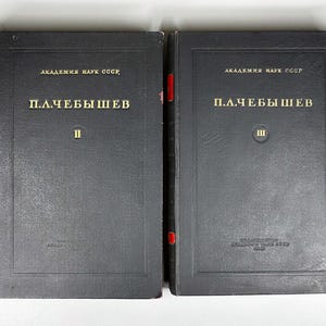 May include: Two vintage black hardcover books. The books have gold lettering that reads "АКАДЕМИЯ НАУК СССР" and "П.Л.ЧЕБЫШЕВ". The first book has the number "II" and the second book has the number "III". The spines have red accents.