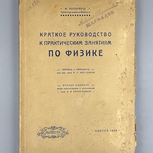 May include: A vintage book with a worn, tan cover. The title, in Russian, reads "Kratkoe Rukovodstvo K Prakticheskim Zaniatiiam Po Fizike." Additional text includes the author's name, publisher, and the year 1924. The book shows signs of age and use.