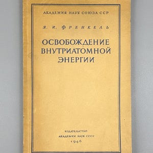 Op de afbeelding: Een vintage boek met een bruinachtige kaft en zwarte tekst. De titel, in het Russisch, luidt "OSVOBOZHDENIE VNUTRIATOMNOI ENERGII." De naam van de auteur is "Ya. I. Frenkel." Het boek is van de Academie van Wetenschappen van de USSR, gepubliceerd in 1946.