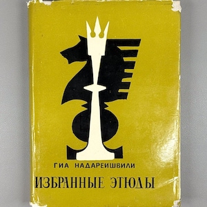 Può includere: Un libro vintage con una copertina giallo senape con una grafica a tema scacchistico in bianco e nero. La grafica include un cavallo, una torre e un pezzo di re. Il titolo e il nome dell'autore sono in russo.