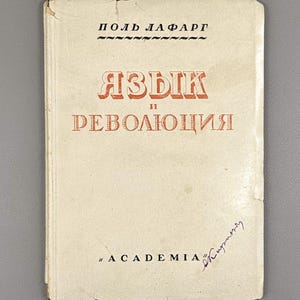 May include: A vintage book with a cream cover. The title, in red Cyrillic letters, reads "Language and Revolution." The author's name, "Paul Lafargue," is printed above the title. The book has a signature and the word "Academia" printed at the bottom.