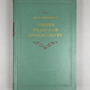 May include: A vintage book with a teal cover and gold lettering. The title, in Russian, reads "Очерки Аварской Диалектологии". The book has decorative gold accents and the year 1962 printed at the bottom.