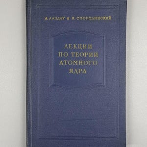 May include: A blue hardcover book with gold lettering. The title, in Russian, reads "Lectures on the Theory of the Atomic Nucleus." The author's names are also in gold. The book has a textured cover.
