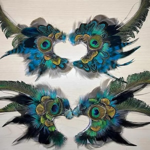 Puede incluir: Cuatro pares de m&aacute;scaras de ojos de plumas de pavo real. Cada m&aacute;scara presenta un dise&ntilde;o central de ojo con plumas azules, verdes y doradas. Las m&aacute;scaras est&aacute;n dispuestas en pares, con los ojos enfrentados.