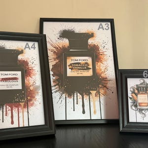 May include: Three framed art prints showcasing Tom Ford perfume bottle designs. The prints are in black frames, with sizes A4, A3, and 6x4 inches. The artwork includes text and abstract paint splatter backgrounds in various colours.