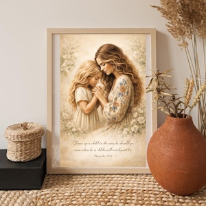 Op de afbeelding: Een ingelijste kunstdruk met een moeder en kind in een tedere omhelzing. Het kunstwerk toont een vrouw en een jong meisje met hun hoofden tegen elkaar, omringd door bloemmotieven. De quote "Train up a child in the way he should go..." is zichtbaar.