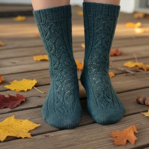 May include: Teal knitted socks with a decorative openwork design. The socks are on a wooden deck with fallen autumn leaves in shades of yellow, red, and brown. The socks are a cozy accessory.