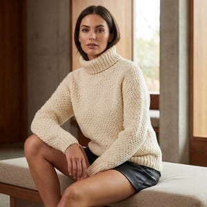 Peut inclure: Pull à col roulé en tricot épais de couleur crème. Le pull présente un motif texturé et des manches longues. Le modèle porte une jupe noire. Le pull est un vêtement chaud et confortable, parfait pour les temps frais.