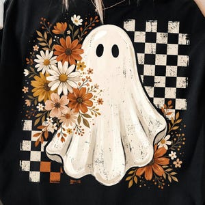 May include: A black t-shirt featuring a central graphic of a white ghost surrounded by a cluster of orange, yellow, and white flowers. The design includes a black and white checkered pattern in the background, creating a contrast with the floral elements.