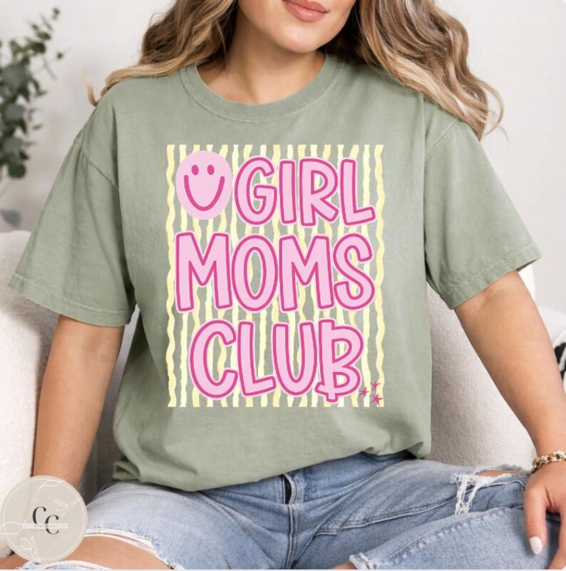 May include: Sage green t-shirt featuring the pink text "GIRL MOMS CLUB" on a background of yellow and white stripes. A pink smiley face is above the word "GIRL".